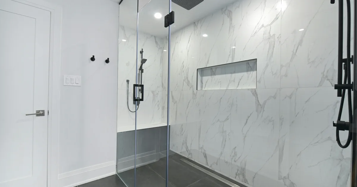 Salle de bain avec douche en verre et murs de marbre