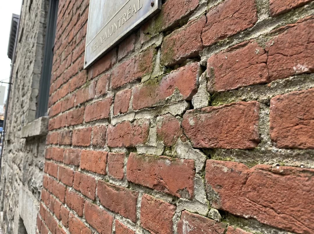 Brick wall with deteriorated mortar joints and a vertical crack
