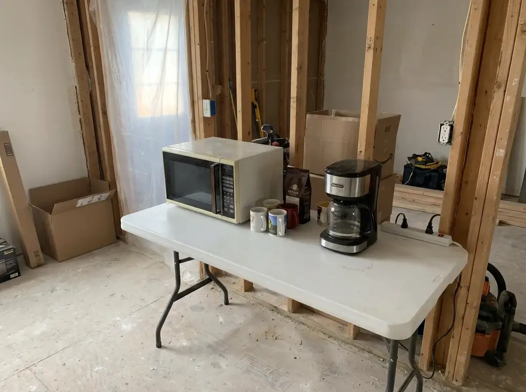 Cuisine temporaire avec micro-ondes et cafetière sur table pliante en chantier