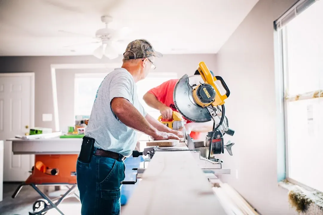 Deux hommes travaillant avec une scie à onglet DeWalt dans une maison en rénovation lumineuse