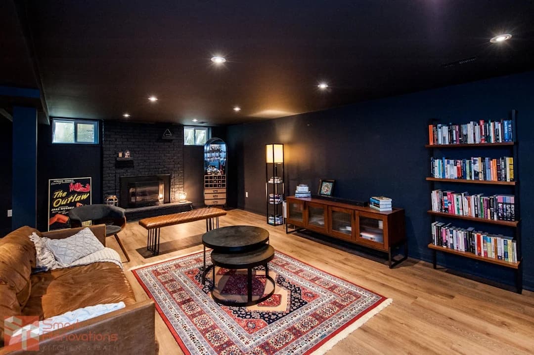 Modern basement lounge with navy walls, warm oak flooring, and black brick fireplace