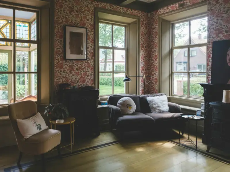 Intérieur d'une maison ancienne avec parquet de bois massif et hautes fenêtres baignées de lumière naturelle