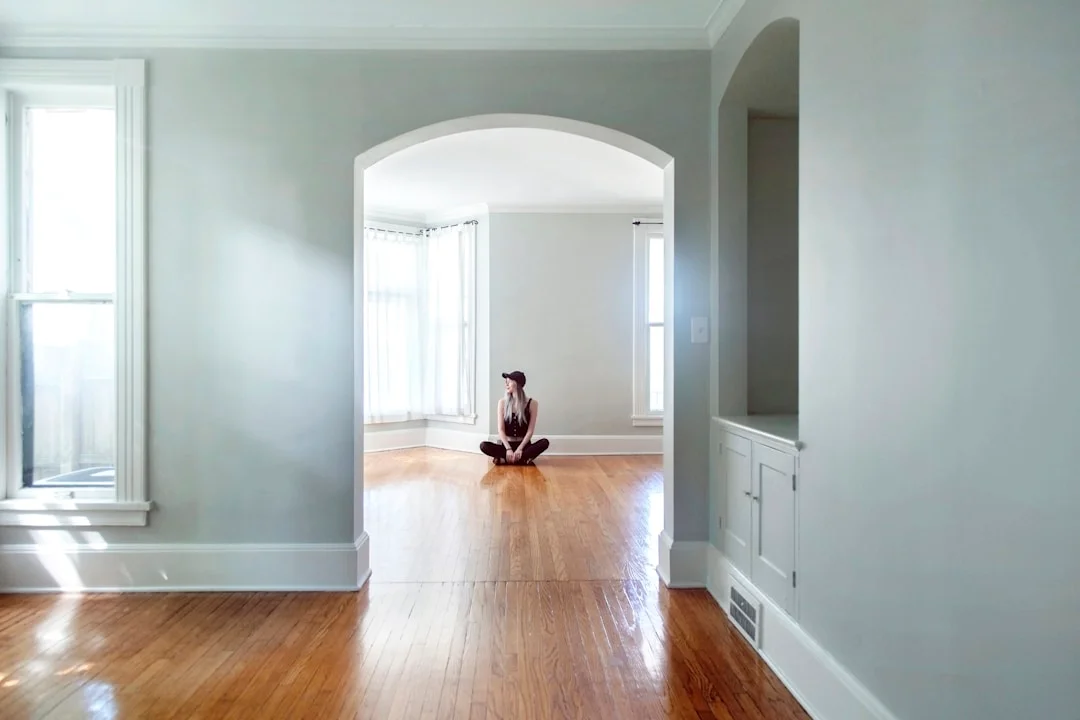 Intérieur patrimonial lumineux avec arche classique et plancher de bois franc d'origine baigné de lumière naturelle