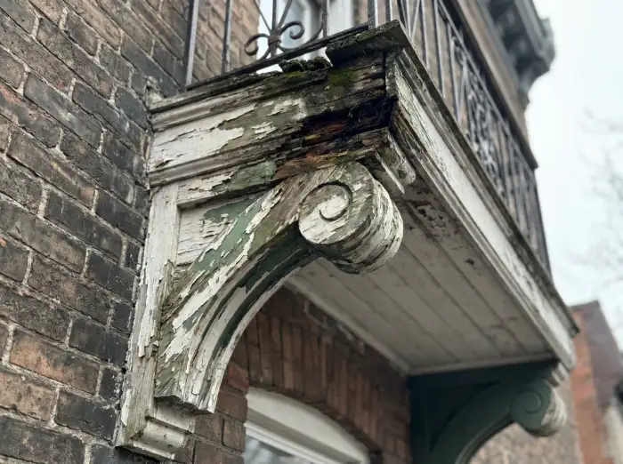Damaged bracket with peeling paint and rot at the top joint