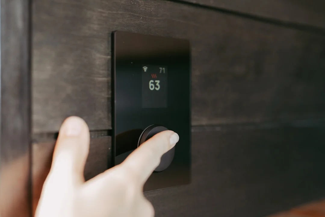 Hand adjusting a digital thermostat display in a modern home