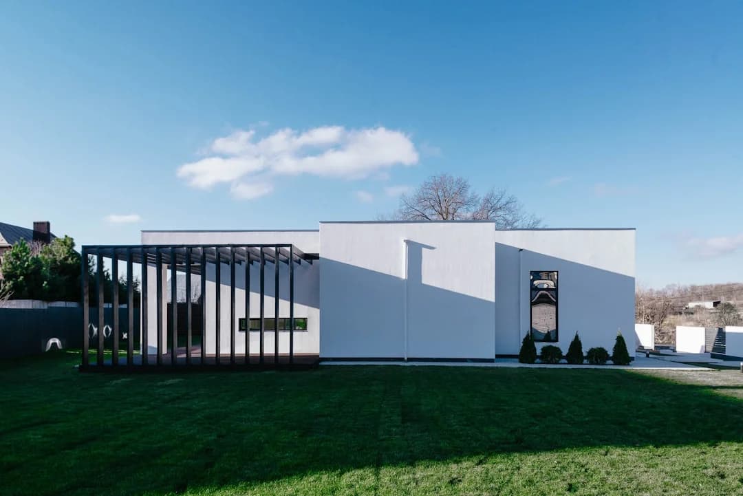 Modern white contemporary house under a spring blue sky with green lawn